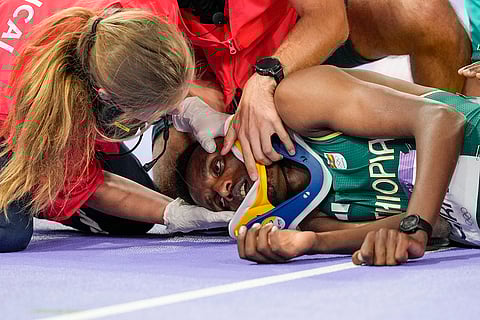 Lamecha Girma, of Ethiopia, is treated on the track after being injured during the men's 3000-meter steeplechase final
